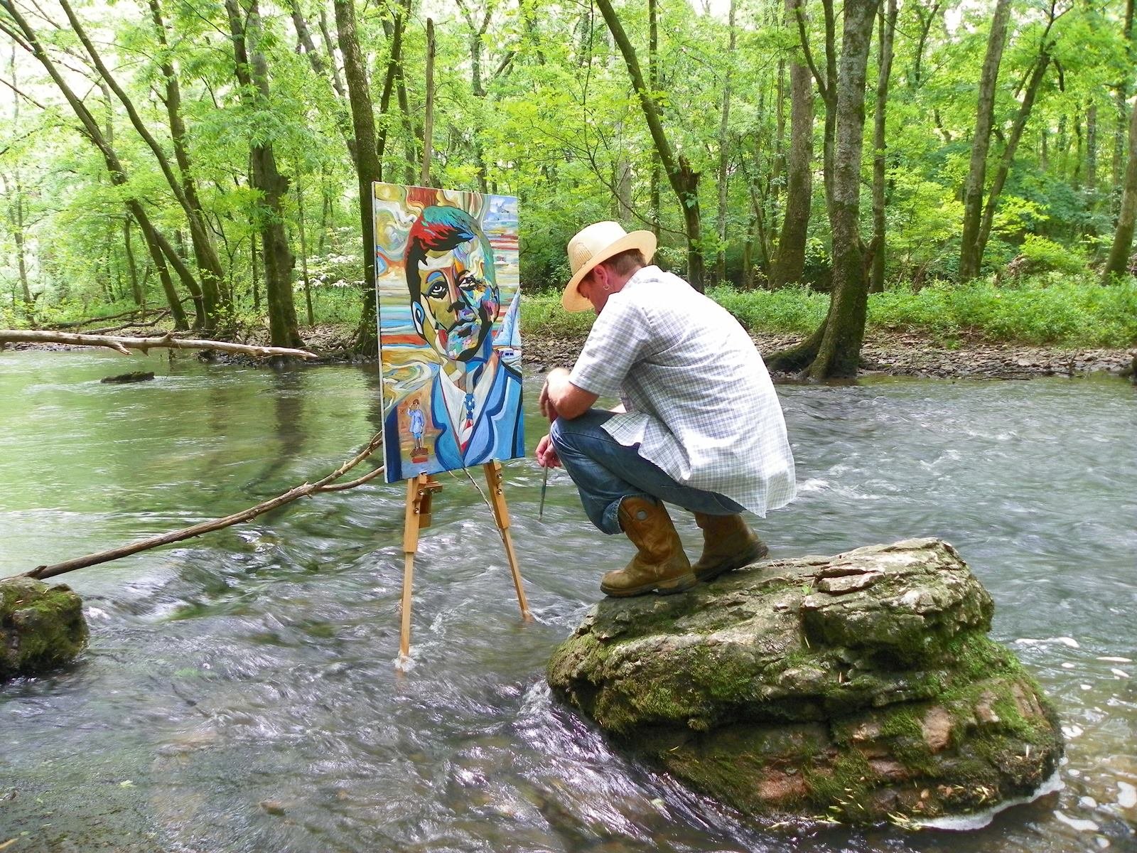 Gray painting a colorful portrait of John F. Kennedy outdoors. PHOTO COURTESY OF BOB GRAY